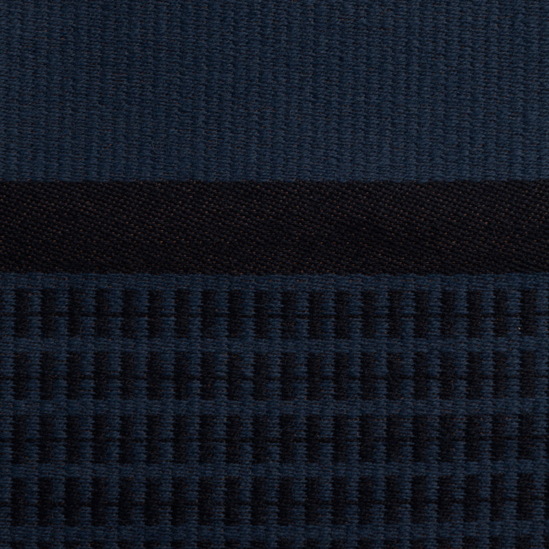 Close-up of the dark blue Danish woven wool fabric from Kjellerup Væveri, featuring a distinctive checkered pattern. The fabric showcases a blend of blue tones, reflecting the exquisite craftsmanship and refined texture characteristic of Kjellerup Væveri's designs, used in the Kelly Rutherford x August Sandgren Limited Edition Collection.
