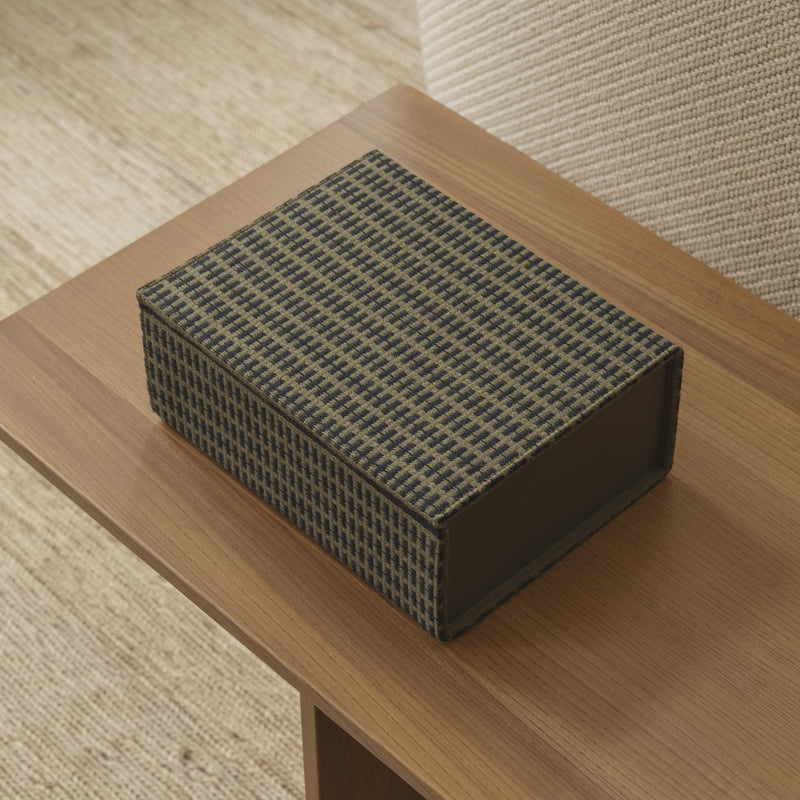 A handcrafted Fusion Bookbox from the Kelly Rutherford by August Sandgren Limited Edition Collection, featuring a distinctive checkered pattern in Danish woven wool fabric, displayed on a wooden surface. The box combines modern Danish design with refined craftsmanship, adding an elegant storage solution to any space.